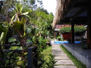 a garden in front of a house with a swimming pool at Kencana Ubud by Mahaputra in Ubud
