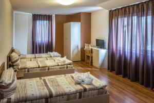 a hotel room with two beds and a desk at Hotel West in Blagoevgrad