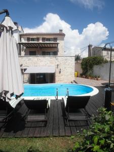 a swimming pool with two chairs and an umbrella at Villa Ester in Rovinj