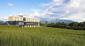 a building in a field with mountains in the background at MT Hotel in Zeltweg