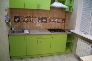 una cocina con armarios verdes y fregadero en Современная 1-комнатная квартира en Járkov
