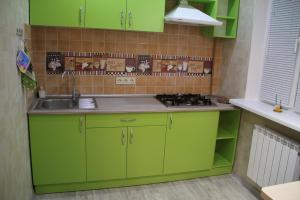 Una cocina con gabinetes verdes y un fregadero. en Современная 1-комнатная квартира, en Járkov