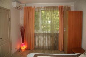 1 dormitorio con ventana y cortina naranja en Современная 1-комнатная квартира, en Járkov