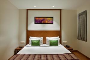 a bedroom with a bed with two green pillows at Hotel Leafio Marigold-Near Airport in Mumbai