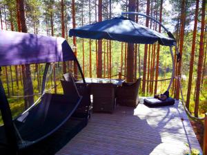 una terraza con una tienda y una mesa en el bosque en Kettu Holl Cottage, en Taipalsaari