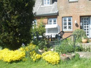 a garden with a bench in front of a house at Pension Peterswarft in Dagebüll
