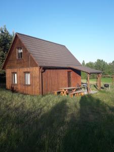 un granero de madera en medio de un campo en Zagroda z Antonówką, en Szypliszki