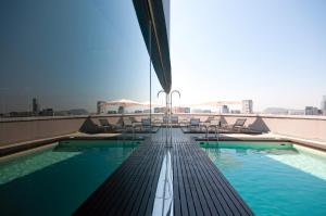 a large swimming pool with a view of the ocean at Hotel Barcelona Condal Mar Affiliated by Meliá in Barcelona