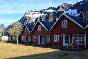 une maison rouge avec des montagnes en arrière-plan dans l'établissement Kaikanten Gryllefjord, à Gryllefjord