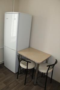 a table and two chairs next to a refrigerator at Современная 1-комнатная квартира in Kharkiv