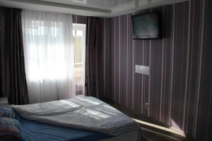 a bedroom with a bed with a window and a tv on the wall at Современная 1-комнатная квартира in Kharkiv