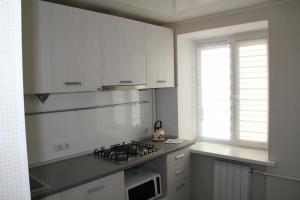 a kitchen with white cabinets and a stove top oven at Современная 1-комнатная квартира in Kharkiv