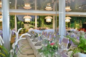 a dining room with white tables and chairs and chandeliers at RAYA Garden - Park Hotel & Winery in Veliko Tŭrnovo