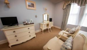 a living room with a television and a dresser with a chair at Dunoon Hotel in Llandudno