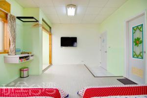 Zimmer mit einem roten Bett und einem TV an der Wand in der Unterkunft Xiang Ting Homestay in Magong