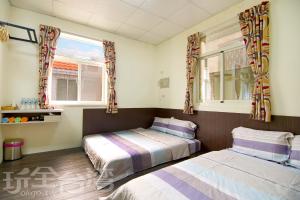 2 Betten in einem Zimmer mit 2 Fenstern in der Unterkunft Xiang Ting Homestay in Magong