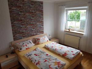 een slaapkamer met 2 bedden en een bakstenen muur bij Benkelberg in Sitzerath