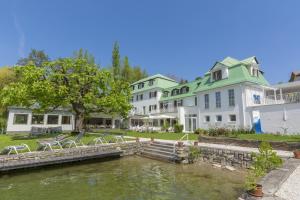 Blick auf den Gasthof vom Wasser aus in der Unterkunft Strandhotel Kärntnerhof in Pörtschach am Wörthersee