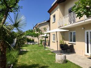 a house with a yard with chairs and an umbrella at Apartments Marjana in Portorož