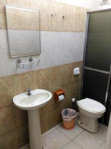 a bathroom with a sink and a toilet and a mirror at Hotel Cristal in Barra Bonita