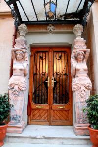 Una porta di legno con due statue di donne sopra. di Sitges Royal Rooms a Sitges