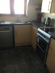 a kitchen with a stove and a sink and a dishwasher at Cairngorm Mountain View in Aviemore