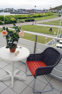 a table and a chair on a balcony with a table and flowers at Hanseat in Helgoland