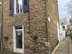 uma casa de pedra com persianas azuis e uma porta em Maison de pêcheur em Cancale