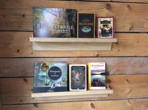 a shelf with books on it on a wooden wall at Le Cottage de la Doucette in Paimpont