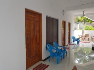 a room with blue chairs and a wooden door at Hilton Cottage in Trincomalee
