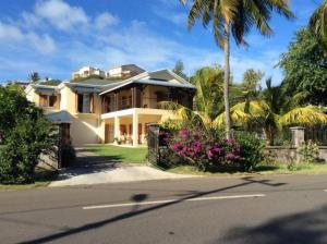 a large house with a palm tree and a street at The Beach House Rodrigues in Rodrigues Island
