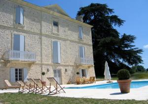 un gran edificio de piedra con sillas y una piscina en Château Mauras en Bommes
