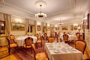 a dining room with tables and chairs and a chandelier at Pałac Tłokinia in Kalisz