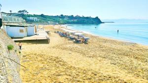 una spiaggia con sedie e ombrelloni e l'oceano di Villa Giada a Partinico