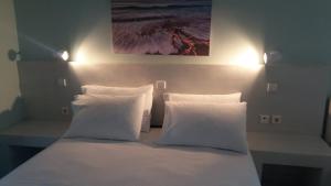 a bed with white pillows and a painting on the wall at Akrogiali Apartments in Agios Ioannis Kaspaka
