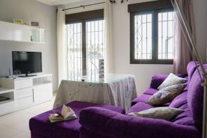 a living room with a purple couch and a tv at "Ventana del Guadalquivir " in Baeza