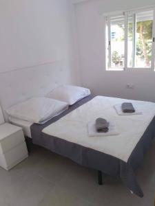 two beds in a white room with towels on them at Apartamento "Pedro" 250 m de la playa in Gandía