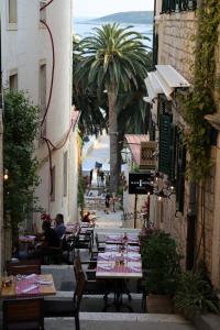 um beco com mesas e cadeiras e pessoas sentadas às mesas em Apartments Sunset em Hvar