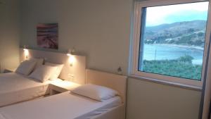 a bedroom with two beds and a large window at Akrogiali Apartments in Agios Ioannis Kaspaka