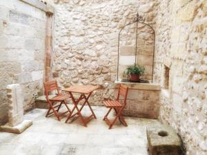 un patio con 2 sedie e un tavolo in una parete di pietra di Dimora Krifò a Martano