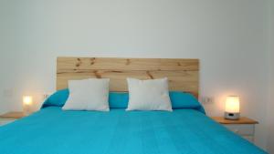 a bedroom with a blue bed with two white pillows at The Beach House in El Médano