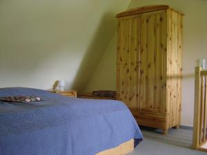ツィングストにあるFerienwohnung am Strandのベッドルーム1室(ベッド1台付)、木製キャビネットが備わります。