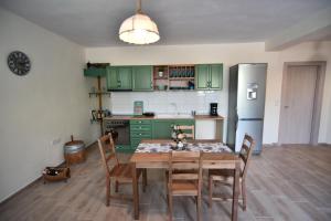 a kitchen with green cabinets and a wooden table and chairs at Searockhouse in Paleo Tsifliki