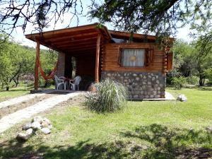 uma cabana com uma mesa e cadeiras à sua frente em Mainame Traslasierra em Los Hornillos