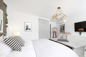 a white bedroom with a bed and a chandelier at Casa Hugo in Pollença