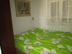 un letto verde con fiori bianchi in una camera da letto di Apartment Ana a Novi Vinodolski