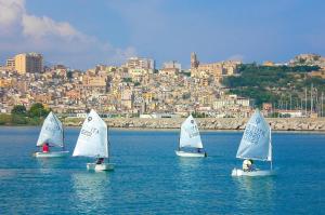 cuatro pequeños veleros en el agua con una ciudad en el fondo en La Casetta di Andrea & Vale, en Termini Imerese