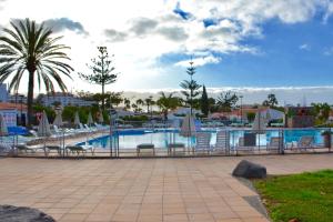 a swimming pool with chairs and umbrellas in a resort at Bungalow en Playa del Ingles in Playa del Ingles