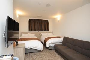 四万十市にあるホテルサンリバー四万十のベッド2台とソファが備わるホテルルームです。
