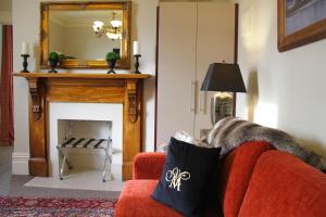 a living room with a red couch and a fireplace at Merivale Manor in Christchurch